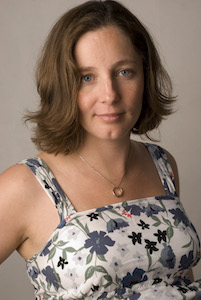 Kim Ward wearing a white and blue floral dress, smiling at the camera 