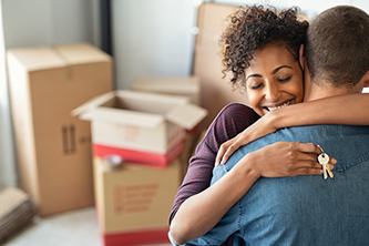 A young couple hugging as they celebrating moving into their new home.