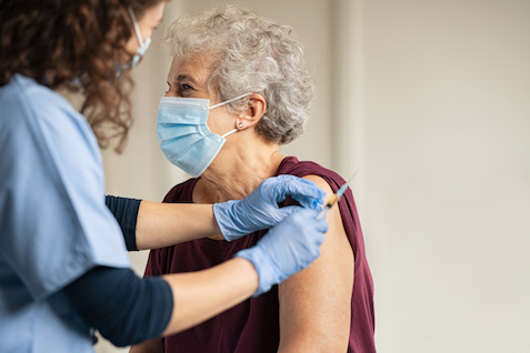 Elderly woman wearing a face mask receiving covid vaccine