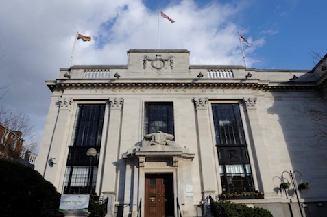 Islington Town hall with the Pride and Great Britain flags flying and a backdrop of a blue and cloudy sky