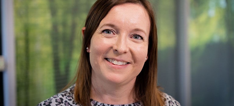 Sian with lush green background smiling