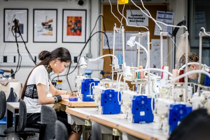 Woman working at a sewing machine in a bright workshop. 