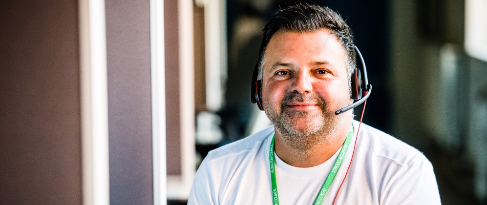 Patric smiling at the camera wearing a headset